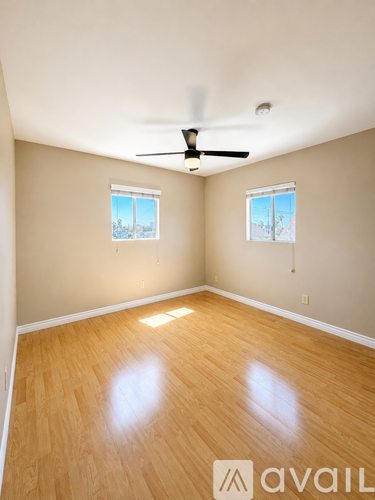 A room with a ceiling fan and two windows.