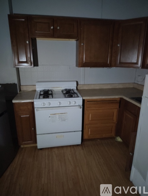 A kitchen with a white stove top oven and wooden cabinets.