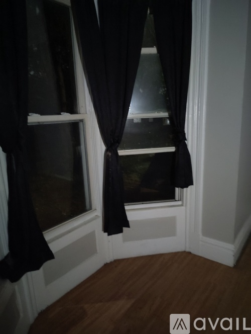 A window with black curtains is open.
