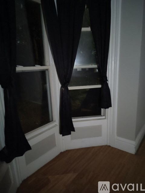 A window with black curtains is open.