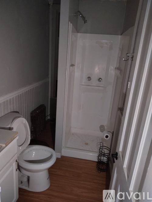 A white toilet in a small bathroom with a walk-in shower.