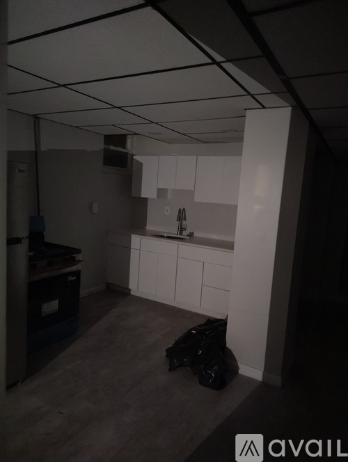 A kitchen with white cabinets and a black bag on the floor.