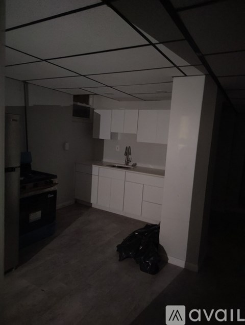 A kitchen with white cabinets and a black bag on the floor.