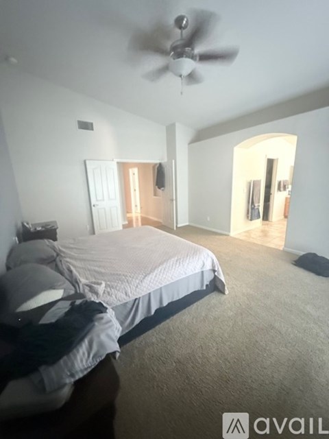 A bedroom with a bed, a ceiling fan, and a mirror.