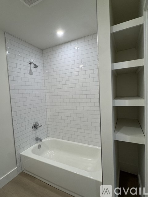 A white bathroom with a white tub and white tiles.