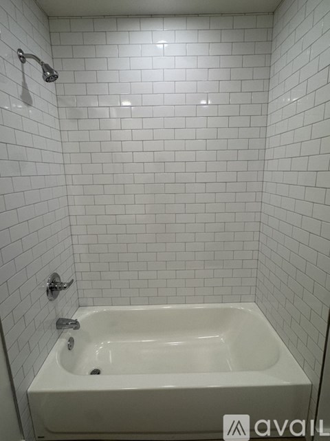A white bathtub in a bathroom with white tiled walls.