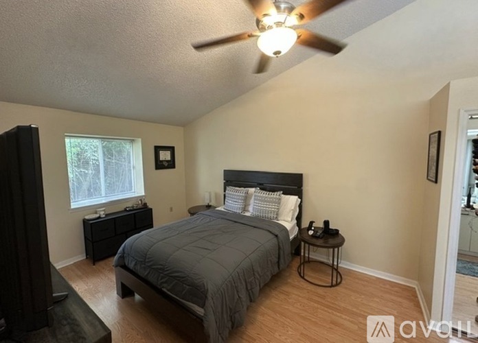 A bedroom with a bed, nightstand, and a ceiling fan.