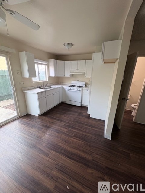 A kitchen with white cabinets and a wooden floor.