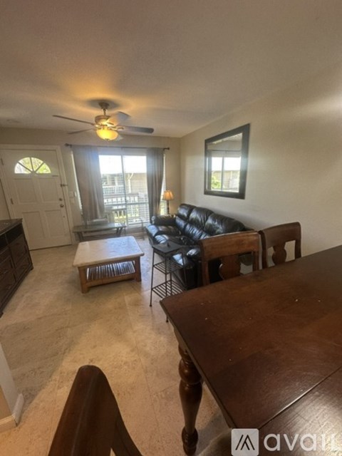 A living room with a brown leather couch and a wooden table.
