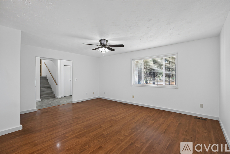 A spacious room with wooden floors and a ceiling fan.