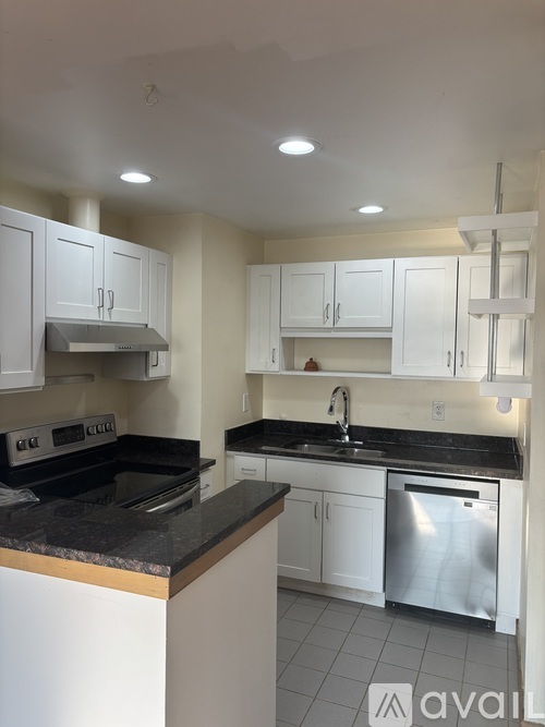 A kitchen with white cabinets and black countertops.