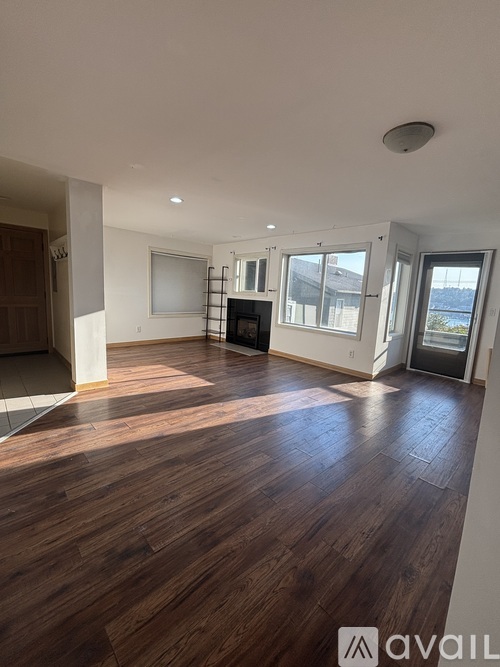 A spacious room with wooden flooring and a flat-screen TV.