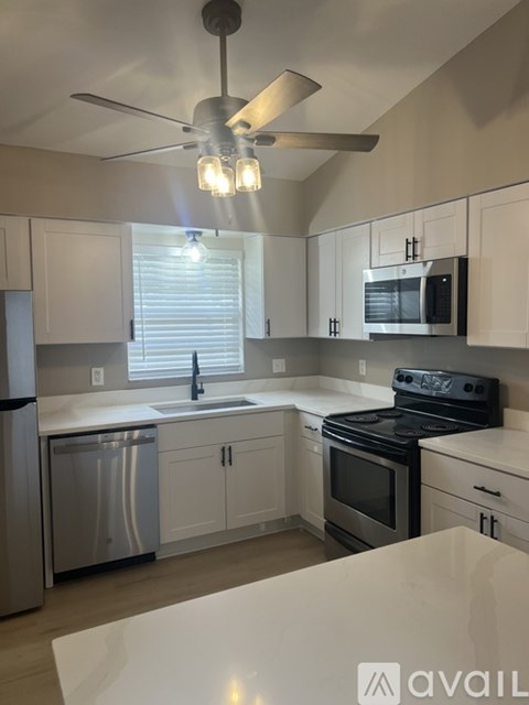 A kitchen with a white counter top and a fan.