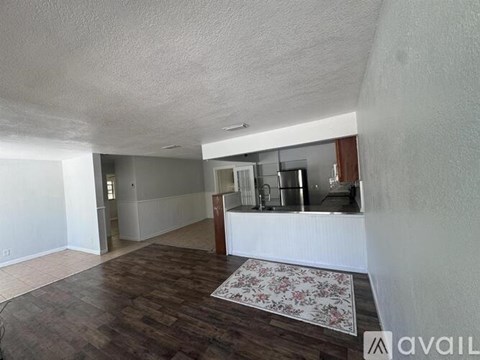 A room with a wooden floor and a rug in the middle.