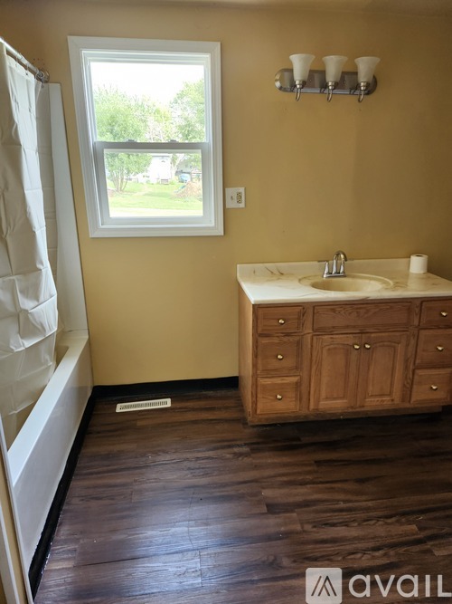A bathroom with a wooden vanity and a window.