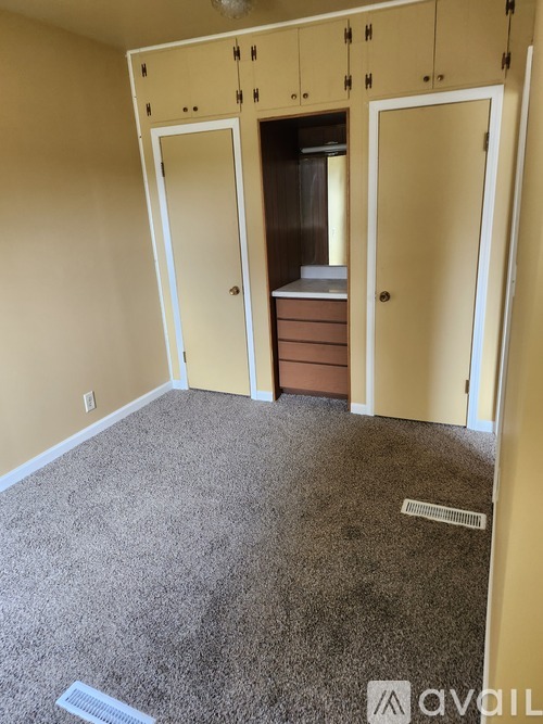 A room with a carpeted floor and a cabinet with a drawer and a shelf.