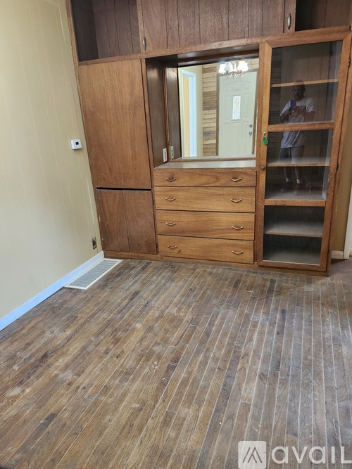 A room with a wooden floor and a wooden wardrobe with glass doors.