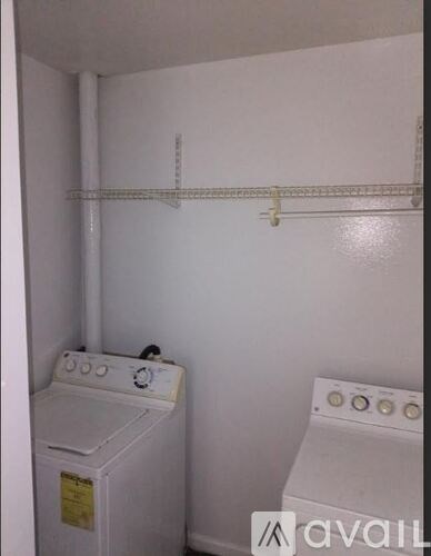 A white wall with a pipe and a clothes dryer.