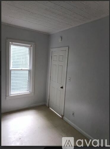 A room with a white door and window with blinds.