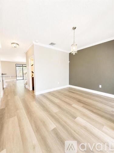 A room with wooden flooring and a chandelier hanging from the ceiling.