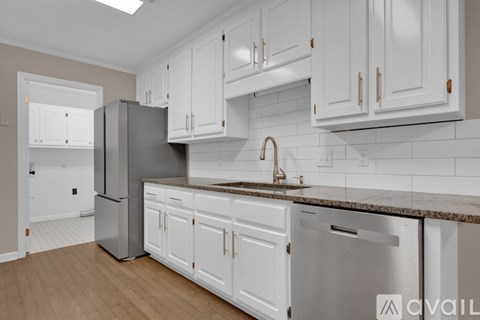 A kitchen with white cabinets and a stainless steel refrigerator.