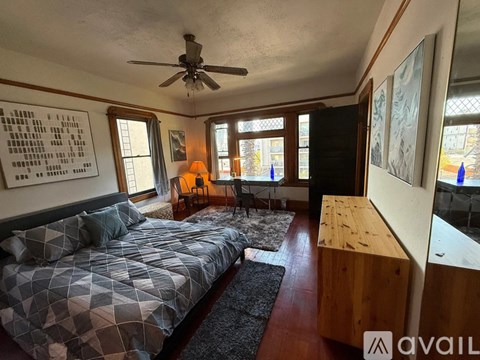 A bedroom with a bed, a chair, and a ceiling fan.