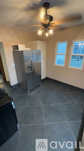 A kitchen with a refrigerator, a ceiling fan, and a black counter.