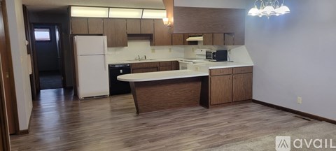 A kitchen with a white fridge and wooden floors.