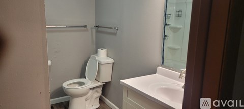 A white toilet with a roll of toilet paper on top of it.