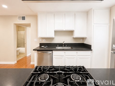A kitchen with white cabinets and a black stove top.