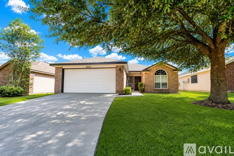 A house with a driveway and a tree in front of it.
