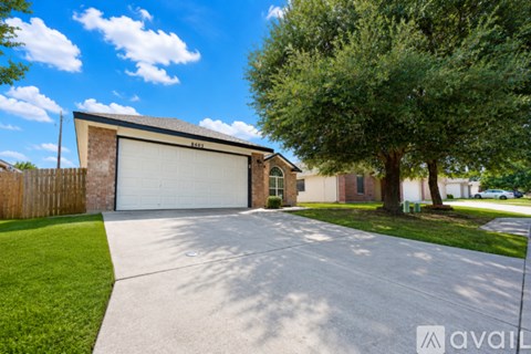 A house with a detached garage and a tree in front.