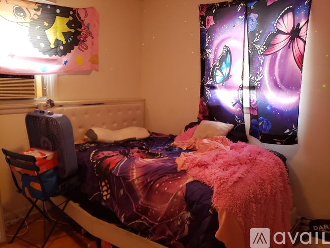 A messy bedroom with a bed covered in a purple comforter and a pink blanket.