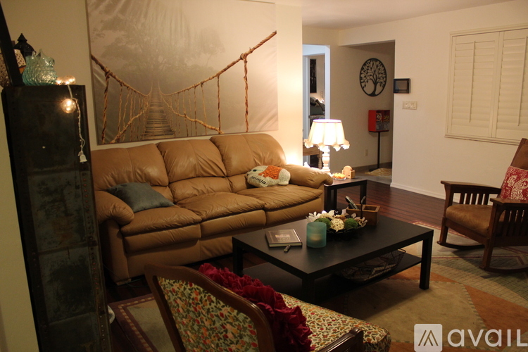 A living room with a brown leather couch, a coffee table, and a hanging swing.