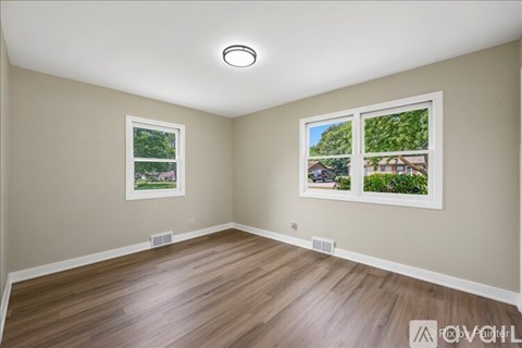 A room with a window showing a view of a house and trees.
