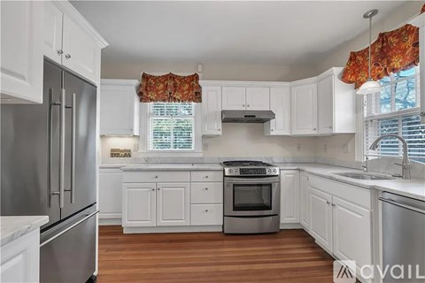 A kitchen with white cabinets and a stainless steel refrigerator.