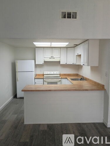 A kitchen with white cabinets and a wooden island.