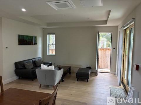 A living room with a couch, chair, ottoman, and a painting on the wall.