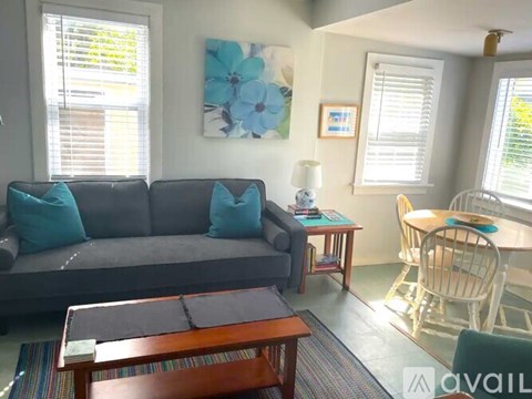 A living room with a grey couch, a wooden coffee table, and a painting on the wall.