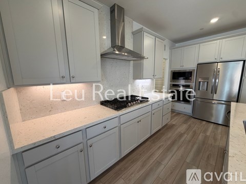 A modern kitchen with white cabinets and a stainless steel refrigerator.