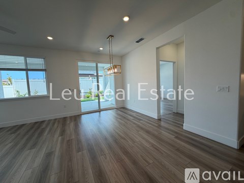 A spacious room with wooden flooring and a large window.