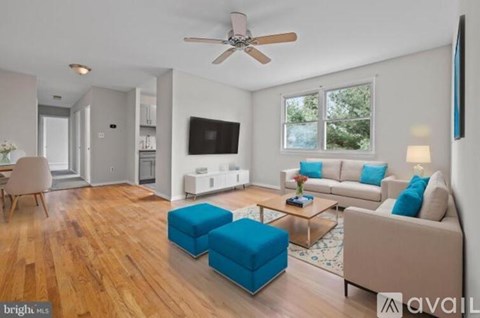 A living room with a wooden floor and a ceiling fan.