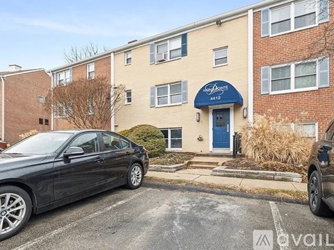A black car is parked in front of a building with a blue awning.