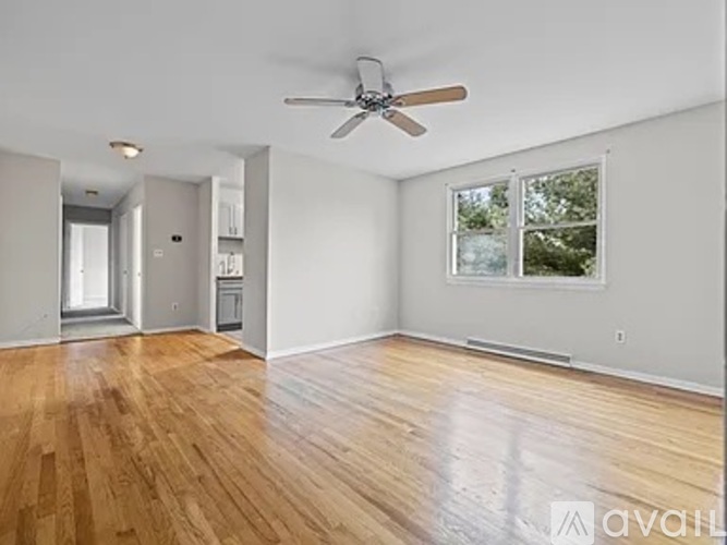 A spacious room with wooden floors and a ceiling fan.