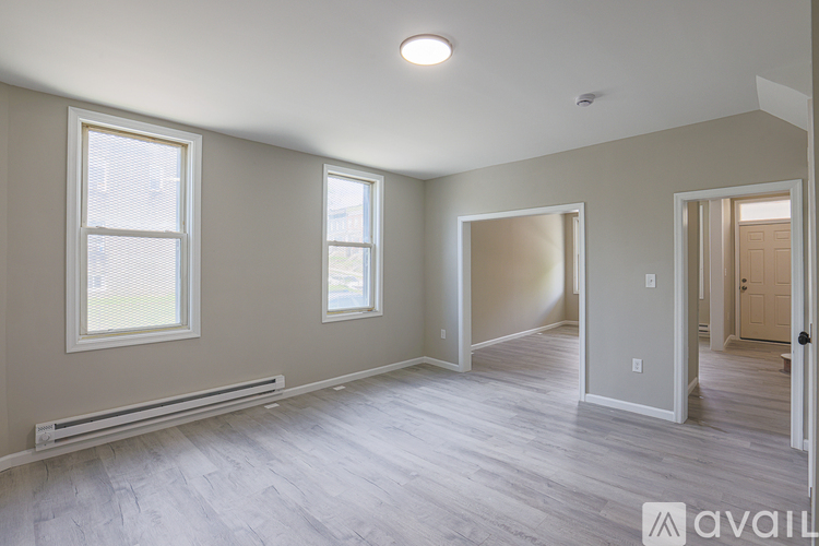 A spacious room with light grey walls and a wooden floor.