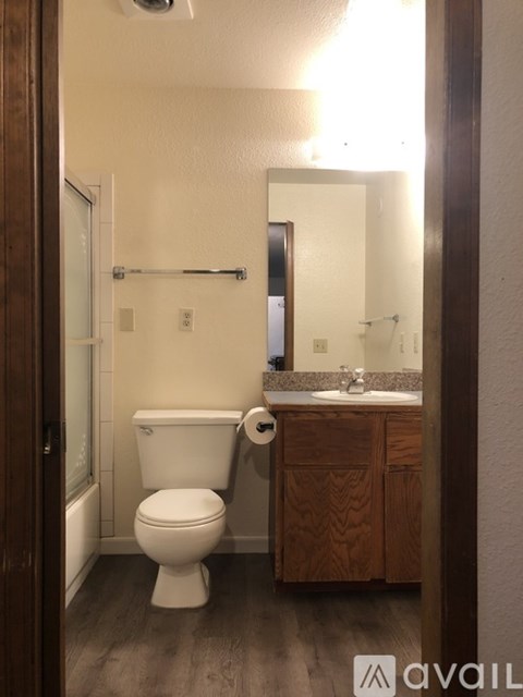 A white toilet with a roll of toilet paper on the holder.