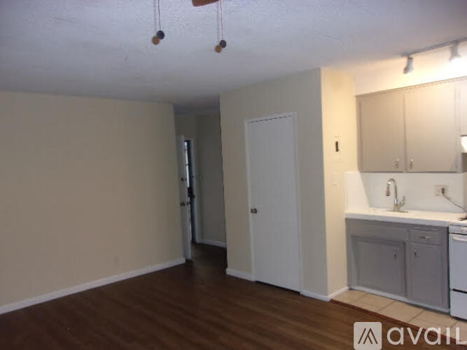A kitchen area with a sink, cabinets, and a door.