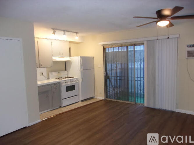 A kitchen with white appliances and wooden floors.