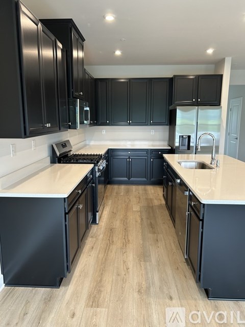 A kitchen with black cabinets and a wooden floor.