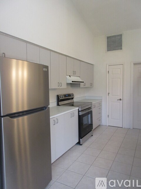 A kitchen with a stainless steel refrigerator and white cabinets.